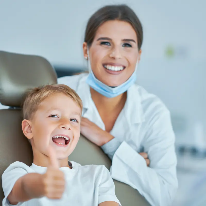 Smiling child giving a thumbs-up with a dentist at Walk in the Park Family Dental in Kitchener